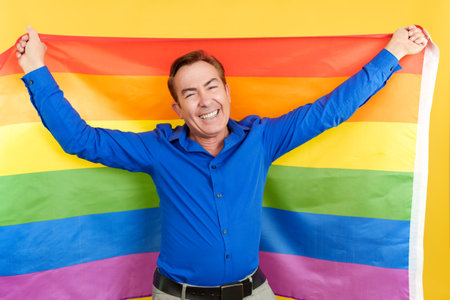 Happy mature man raising a lgbt rainbow flagの写真素材