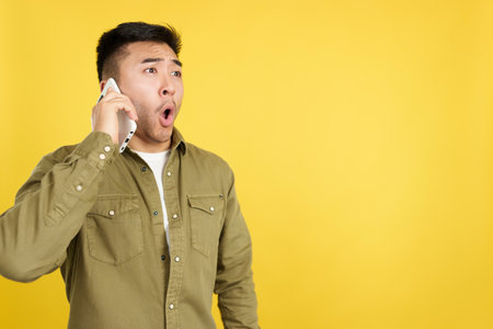 Surprised chinese man talking to the mobileの写真素材