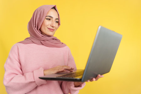 Happy muslim woman standing using a laptopの写真素材