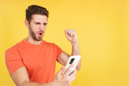 Excited man celebrating while using the mobile phoneの写真素材