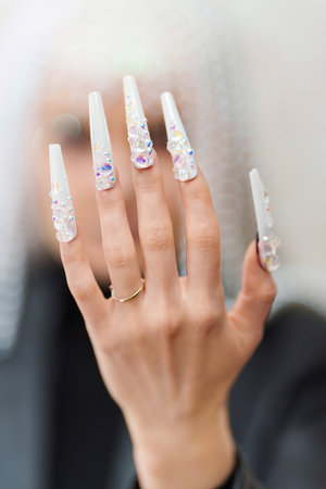 Female hand with white and long fake nailsの写真素材