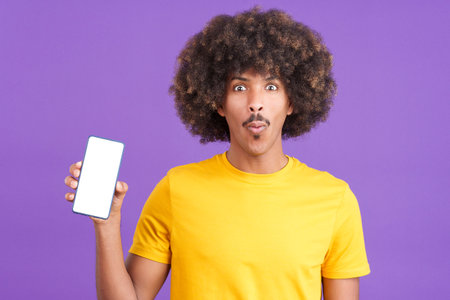 Surprised african man holding a mobile with a blank screenの写真素材