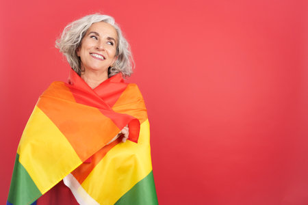 Smiley mature woman wrapped with a lgbt flagの写真素材