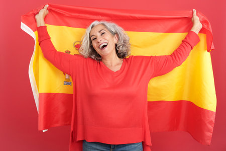 Happy mature woman raising a spanish national flagの写真素材