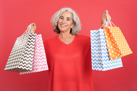 Happy mature woman standing showing shopping bagsの写真素材