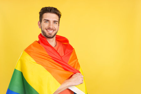 Happy caucasian man wrapped with a lgbt flagの写真素材