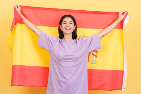 Happy caucasian woman smiling and raising a spanish national flagの写真素材