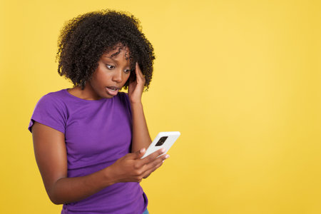 Worried woman with afro hair using a mobile phoneの写真素材