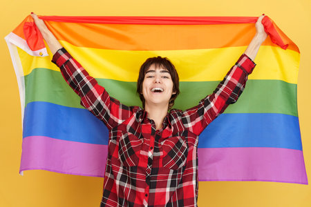 Androgynous person raising a lgbt rainbow flagの写真素材