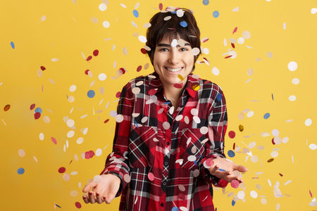 Happy androgynous person surrounded by flying confettiの写真素材
