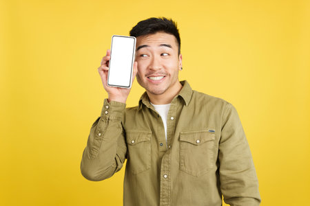 Cool chinese man holding a mobile with a blank screenの写真素材