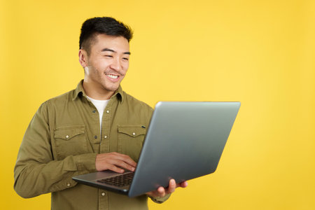Chinese man smiling while using a laptopの写真素材