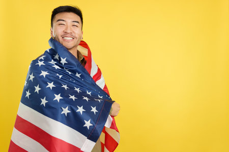 Happy chinese man wrapping with a United States national flagの写真素材