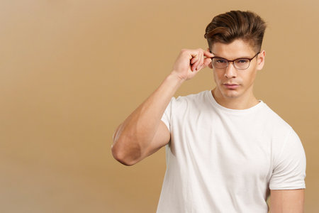 Sensual man taking off the eyeglasses while looking at cameraの写真素材