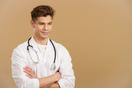 Handsome doctor smiling with arms crossed looking awayの写真素材