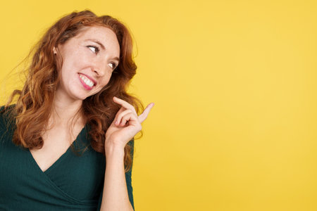 Happy redheaded woman pointing a blank space to the sideの写真素材