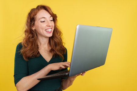 Happy redheaded woman using a laptop while smilingの写真素材