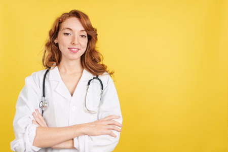 Redheaded female doctor smiling at the camera with arms crossedの写真素材