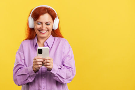 Mature woman listening to music with headphones and a mobileの写真素材
