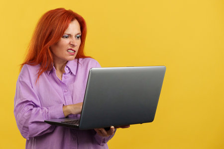 Mature redheaded woman having a problem with a laptopの写真素材