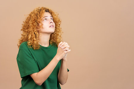 Woman looking up while praying with folded handsの写真素材