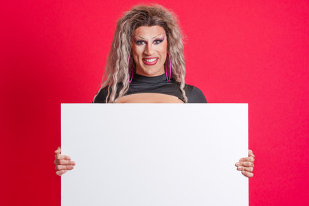 Smiley transgender person holding a blank panel in studioの写真素材