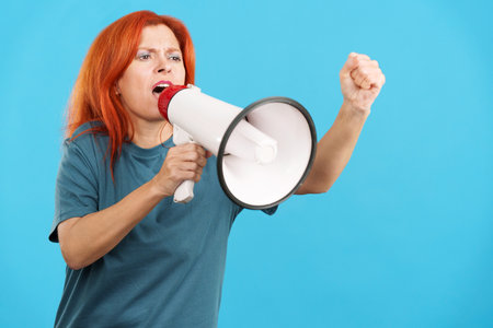 Upset redheaded mature woman yelling using a loudspeakerの写真素材