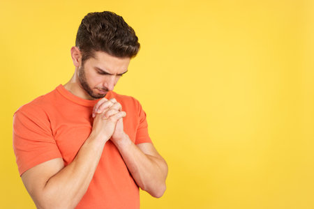 Caucasian man praying with folded hands looking downの写真素材