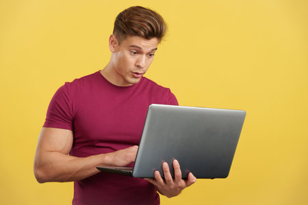 Surprised strong man standing using a laptopの写真素材