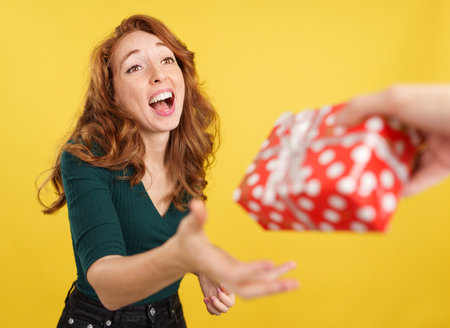 Cool redheaded woman smiling while receiving a giftの写真素材