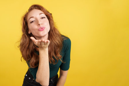 Redheaded woman blowing a kiss while looking at the cameraの写真素材
