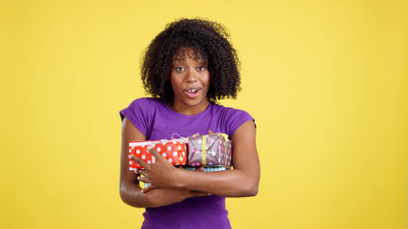 Woman with afro hairstyle smiling at the camera holding giftsの写真素材