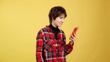 Androgynous person celebrating while using a mobileの写真素材