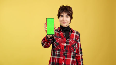 Androgynous person showing a green mobile screenの写真素材
