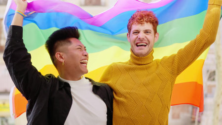 Excited gay couple waving a lgbt flag on the balconyの写真素材