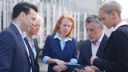 Businessman dividing tasks among his employees while using a tabletの写真素材