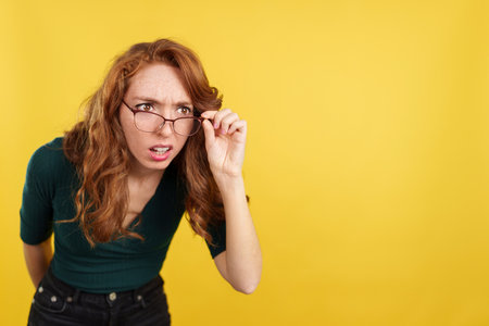 Redheaded woman with glasses spying with curiosityの写真素材