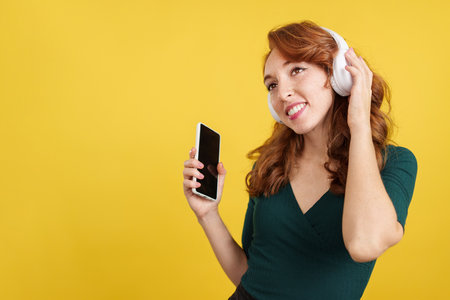 Relaxed redheaded woman listening to music looking upの写真素材