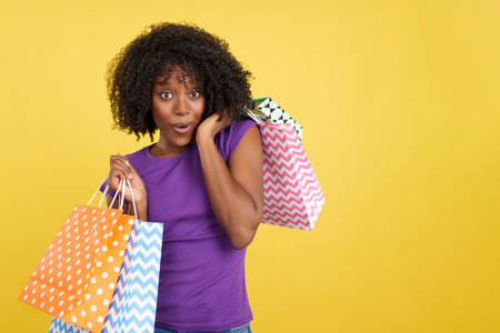 Greedy woman with afro hair holding many shopping bagsの写真素材
