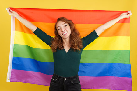 Happy redheaded woman raising a lgbt rainbow flagの写真素材