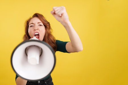 Angry redheaded woman shouting using a loudspeaker