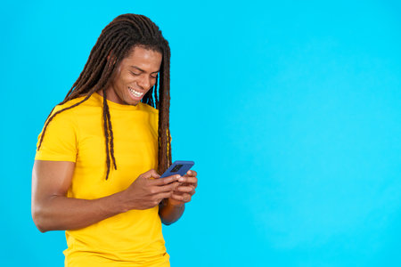 Happy latin man with dreadlocks smiling while using the mobileの写真素材