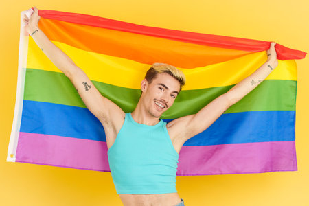 Proud gay man raising a lgbt rainbow flagの写真素材