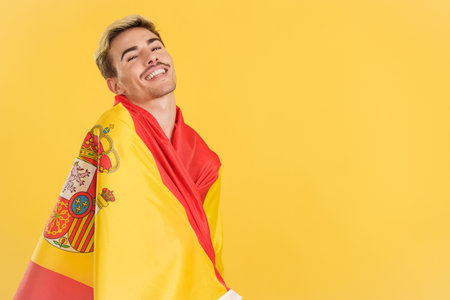 Happy gay man wrapping with a spanish national flagの写真素材