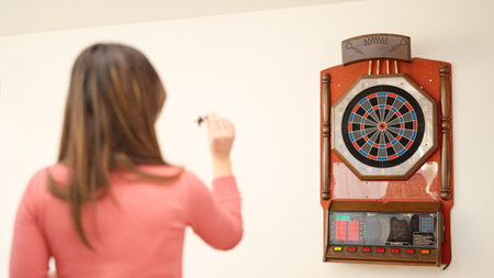 Rear view of a woman playing darts at homeの写真素材