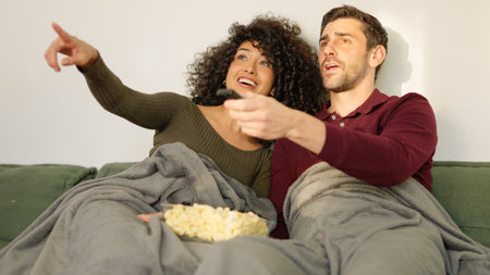 Multi-ethnic couple switching channel on tv with remote control