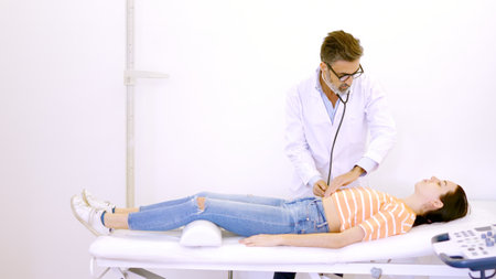 Doctor auscultating the patients abdomen with a stethoscope