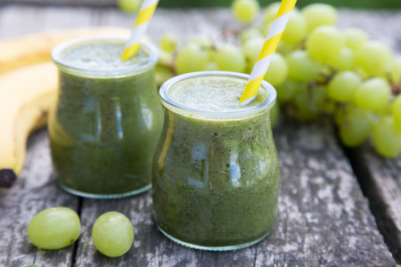 Healthy detox green smoothie with spinach, grape and banana on old wooden tableの写真素材