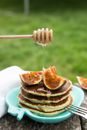 making pancakes with figs and honey in the garden on a rustic table. sunlight, selective focusの写真素材
