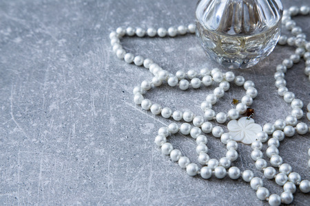 a strand of pearls and perfume on a stone backgroundの写真素材